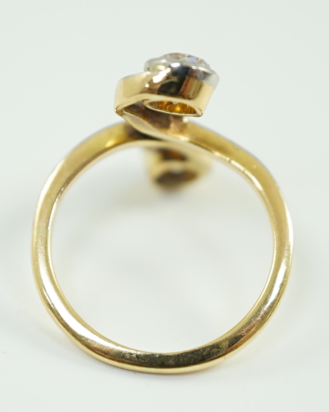 An early to mid 20th century gold and two stone diamond cross over ring, with five stone diamond chip setting